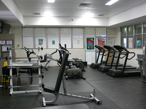 Inside of fitness centre showing fitness equipment including treadmills, exercise bikes and weightlifting equipment.