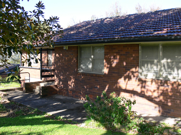 Small single storey brick accommodation cottage. There are three steps leading to the entrance.