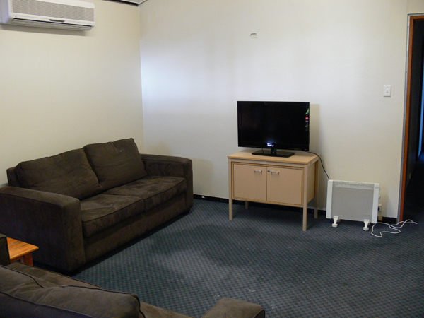 Room with two 2-seater lounges, a small TV on a cupboard, and heater.