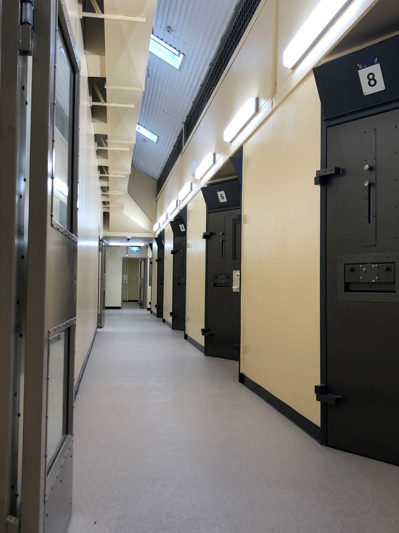 Brightly lit corridoor showing doors of 3 cells