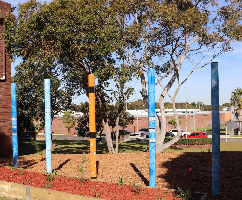 5 poles standing 1 metre apart in a row, in shades of sky blue, light blue and orange
