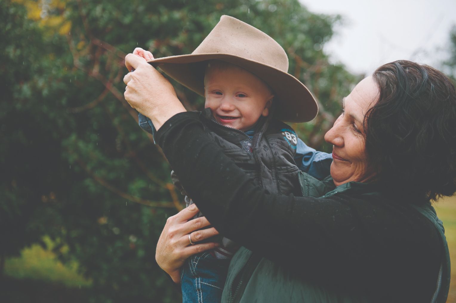 An adult female holding a male toddler and dancing smiling 